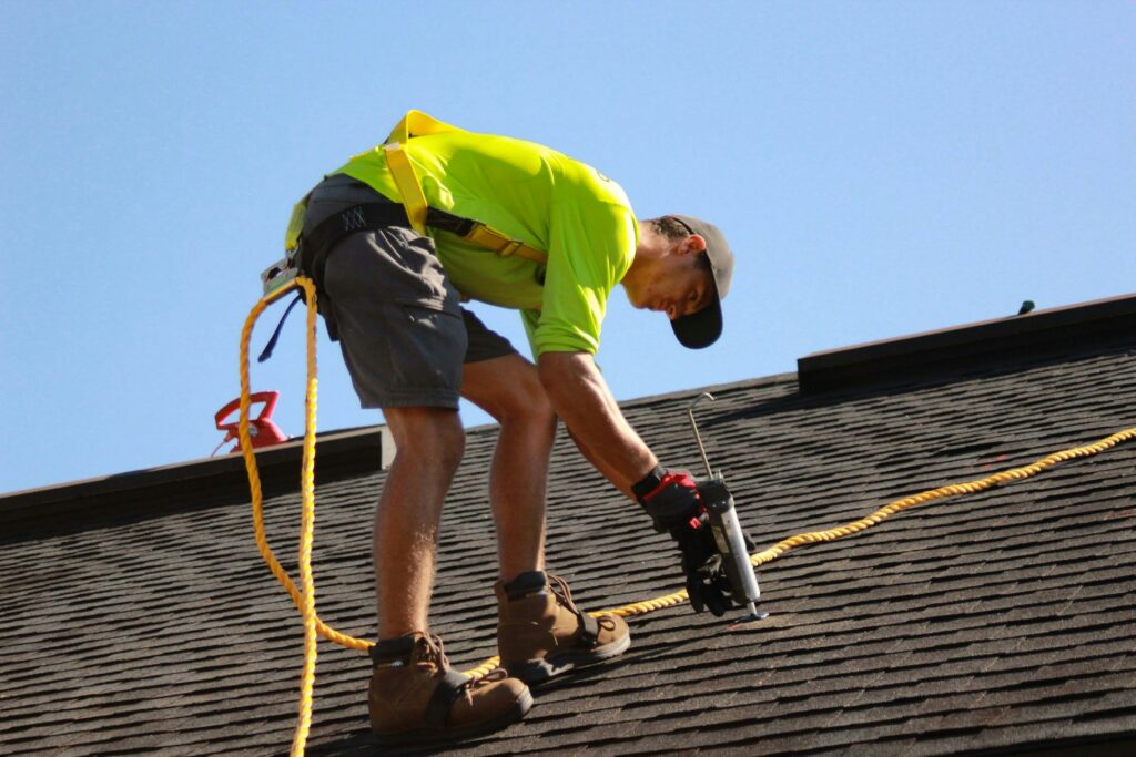Roofer using a nail gun on shingles