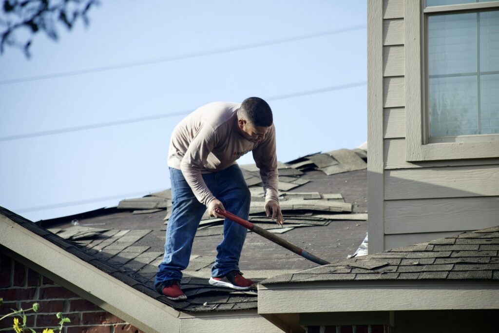 Roofer removing old shingles during a tear-off