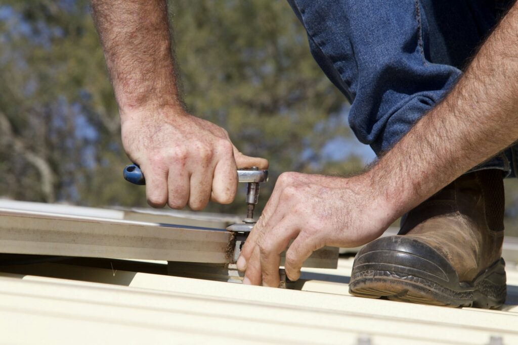 Hands fastening metal roofing panels